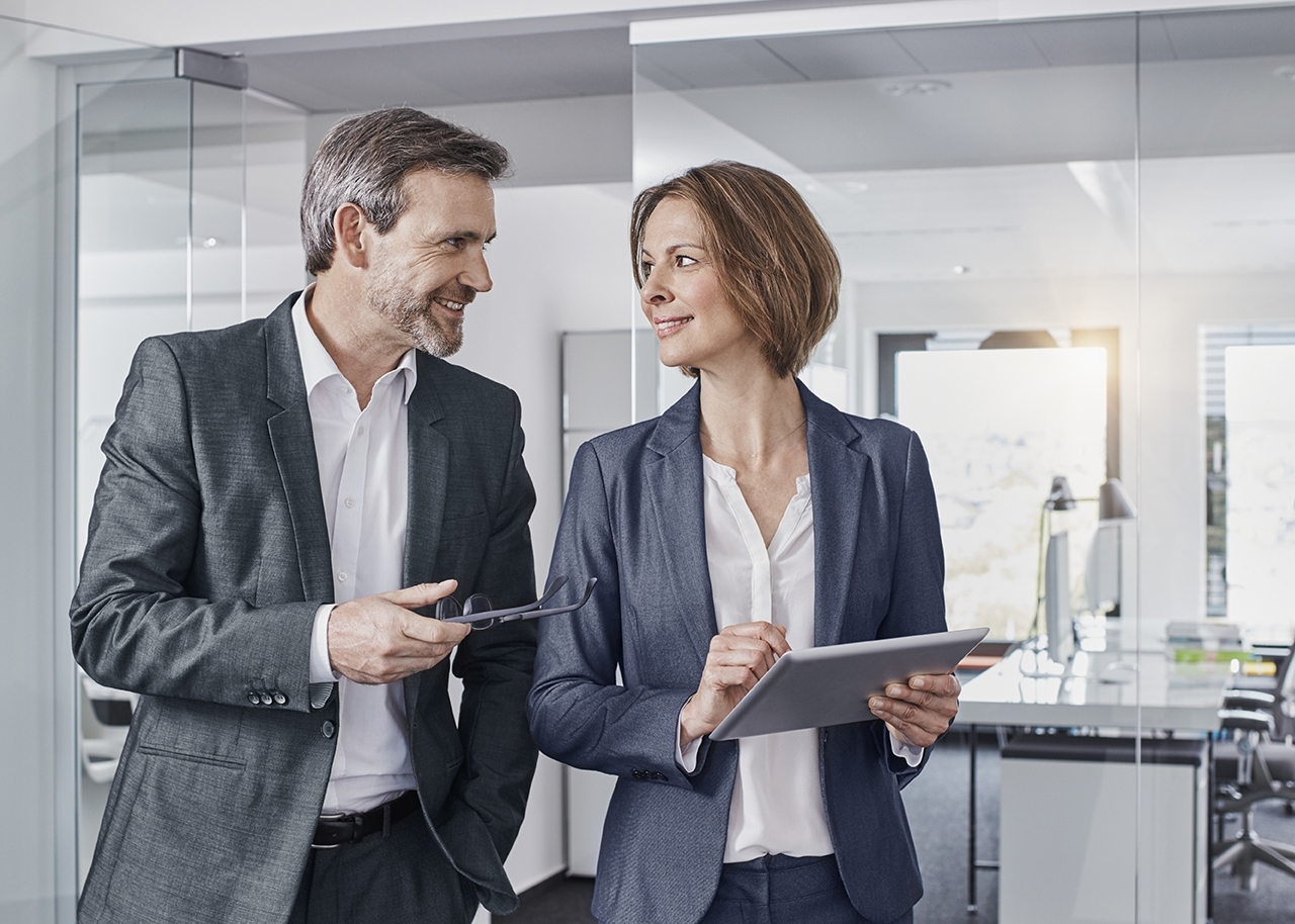 Smiling businessman and businesswoman using tablet in office together 